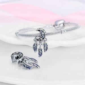 Detailed shot of silver dreamcatcher moon charms with blue feathers on a snake chain