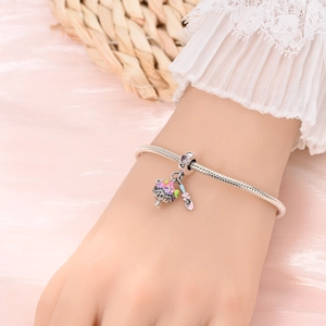 Detailed close-up of a silver charm bracelet featuring a colorful enamel sundae and spoon