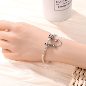 Detail of silver snake chain bracelet featuring astronaut and rocket charms with blue stones