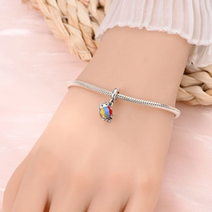 Gros plan détaillé d'un bracelet serpent en argent avec un pendentif chat coloré sur un poignet