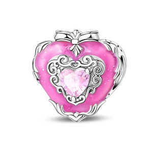 Macro view of heart-shaped charm with pink enamel and center crystal bow detail