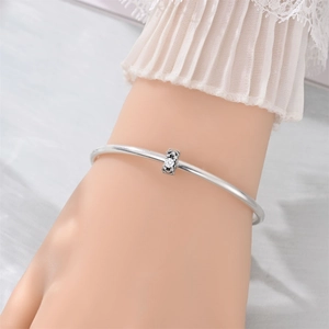 Close-up of elegant silver open bangle featuring a rectangular zircon centerpiece on a wrist