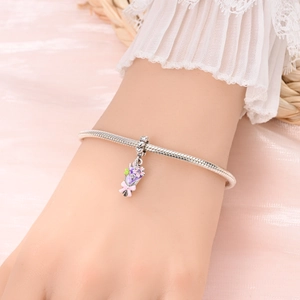 Close-up of a silver charm bracelet featuring a colorful enamel flower bouquet pendant