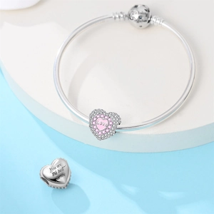 Detail of silver heart charm with pink enamel Love engraving and snake chain bracelet