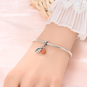 Silbernes Schlangenarmband mit Blattanhänger und orangem Edelstein-Charm am Handgelenk