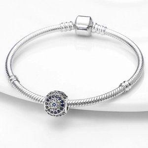 Macro-opname van zilveren slangenarmband met blauwe zirkoon boze oog bedel detail