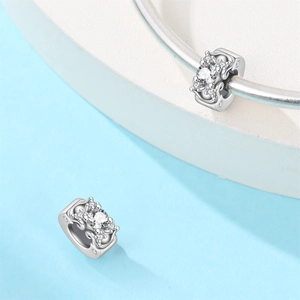Detailed view of silver-tone hollow charm beads with clear stones on a sleek bangle