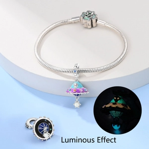 Detailed view of silver astronaut charm with luminous enamel and star detail on bracelet