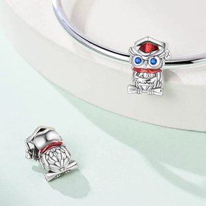 Silver owl graduation charm with blue gemstone eyes and red enamel hat on a bracelet