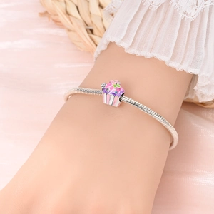 Close-up of a silver charm bracelet featuring a sweet pink enamel cake pendant with zircon
