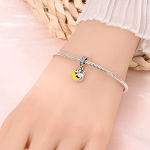 Détail d'un bracelet en argent avec pendentif chat en émail blanc et lune jaune brillante