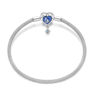 Close-up of silver mesh bracelet with heart-shaped moon and star enamel pendant