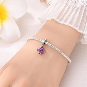 Gros plan d'un bracelet serpent en argent avec un pendentif poisson en émail violet au poignet