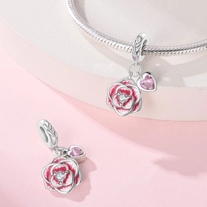 Detailed view of silver-plated rose and pink heart charms on a snake chain bracelet