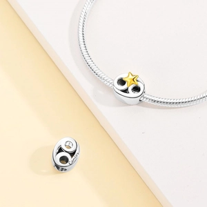 Macro shot of silver Cancer zodiac charm with gold star on a snake chain bracelet