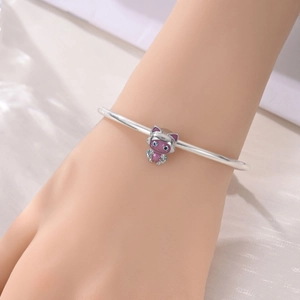 Gros plan d'un bracelet en argent avec une breloque chat en émail violet et bleu