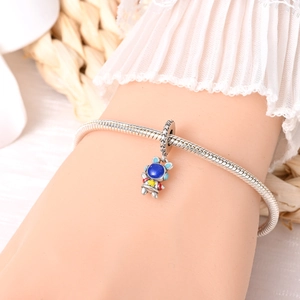 Detail of silver astronaut charm on snake chain bracelet worn on wrist for daily styling