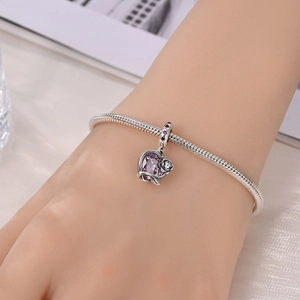 Detail of silver snake chain bracelet featuring a large purple heart crystal pendant