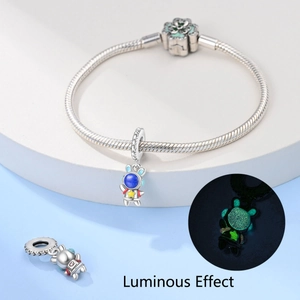 Detailed view of astronaut charm with luminous effect on snake chain bracelet