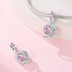 Detail of pink heart zircon pendant with silver rose on snake chain bracelet