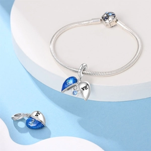 Detail view of heart-shaped love charm and silver snake bone bracelet with blue enamel
