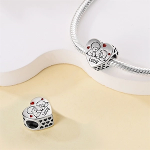 Detailweergave van zilveren hartvormige bedel met LOVE-gravure en roze accenten aan armband