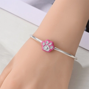 Close-up of silver open bangle featuring a pink enamel paw print charm with micro-set zircons