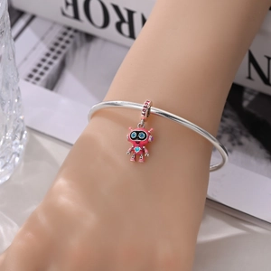 Detailed close-up of a silver charm bracelet featuring a pink robot pendant with a blue heart
