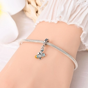 Close-up of a silver astronaut charm with enamel details on a snake chain bracelet