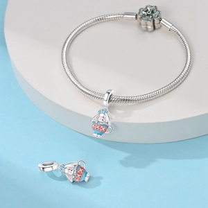 Gros plan de charms lapin et tasse en émail bleu sur un bracelet en argent