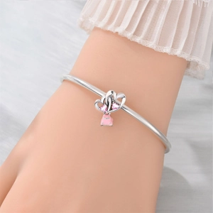 Silver bangle with double pink crystal hearts and a pink car charm worn on a wrist