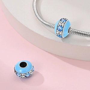 Detail of sky blue macaron charm with parallel crystal settings on silver bracelet