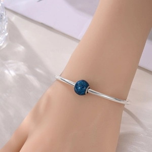 Bracciale rigido argento con perla blu scuro vintage indossato al polso di una donna