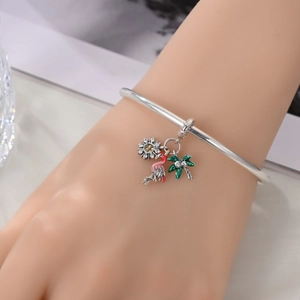 Silver charm bracelet featuring pink flamingo, sunflower and palm tree pendants on wrist