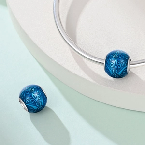 Vista macro di un ciondolo a fiore in smalto blu su un bracciale a cerchio in argento