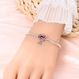 Detail of a silver charm bracelet with pink enamel heart and LOVE pendant on a wrist