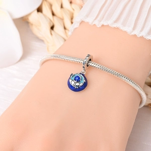 Close-up of a silver astronaut charm with blue enamel starry detail on a snake chain bracelet