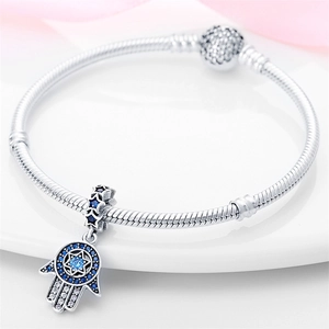 Macro-opname van Hamsa Hand-bedel met blauwe zirkonia op een zilveren slangenarmband