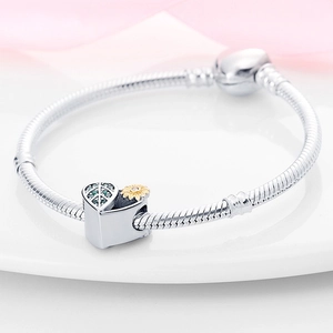 Macro shot of silver snake chain with heart charm and golden sunflower bead detail