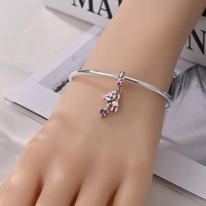 Close-up of a silver koala charm with pink enamel and a purple heart zircon on a bangle