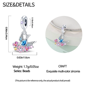 Detailed close-up of a silver swallow charm with blue gemstones and floral accents