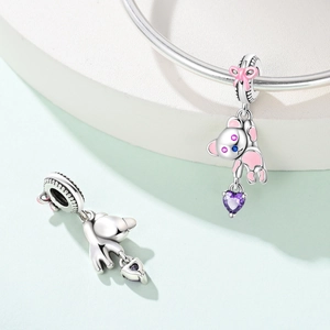 Macro view of silver koala charm with pink enamel and a purple heart gemstone detail
