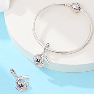 Detail of silver wedding charm with bride, groom and pink stones on snake chain bracelet