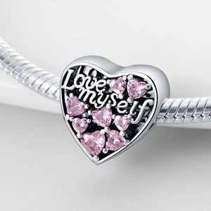 Macro shot of heart charm with Love Myself engraving and pink zircon on silver chain