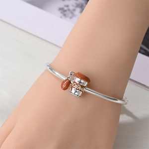 Detailansicht eines silbernen Kaffee-Armbands mit Miniatur-Kaffeetasse und Kaffeebohnen
