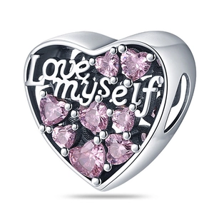 Detailed macro of silver heart charm featuring Love Myself engraving and pink gemstones