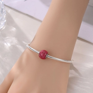 Bracciale minimalista in argento con perlina incisa a rosa rossa indossato al polso