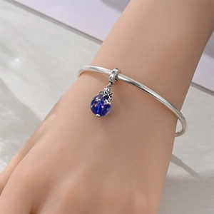 Detail of silver bangle with starry blue glass charm and star engraving on model's wrist
