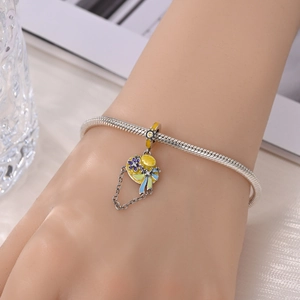 Silver snake chain bracelet with yellow straw hat charm featuring purple flowers and fringe