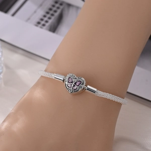 Close-up of silver mesh bracelet with heart-shaped purple butterfly charm on wrist